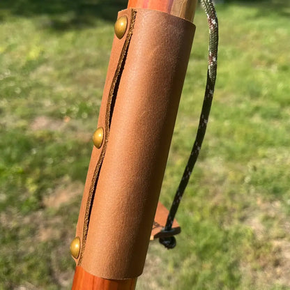 Leather grip with brass buttons on red cedar ball knob walking cane, camo paracord wrist strap detail
