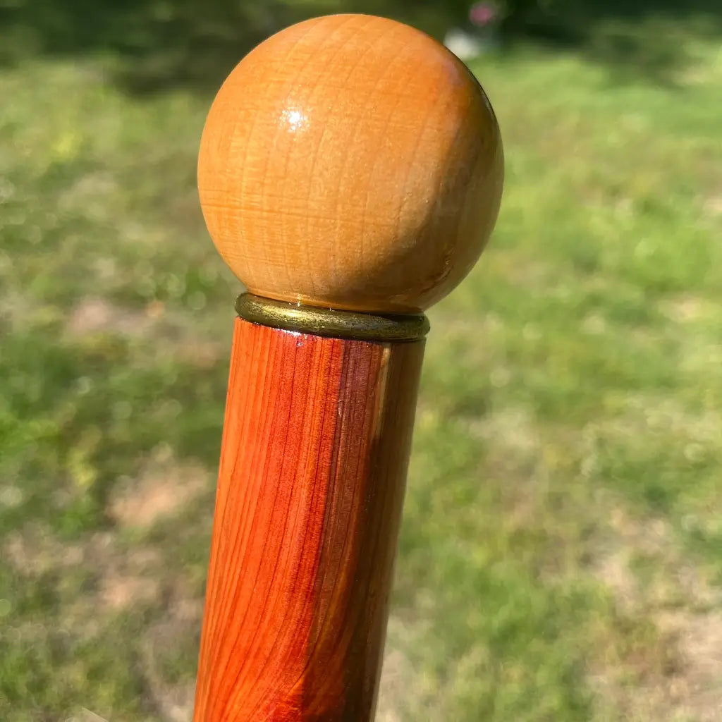 Close-up of wooden ball knob handle and brass collar on red cedar walking cane
