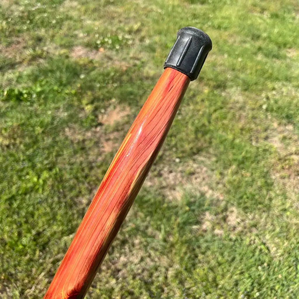 Side angle of rubber walking cane black rubber tip.  It is on a beautiful tapered red cedar cane shaft.  Tip has some ridges on the side of it.