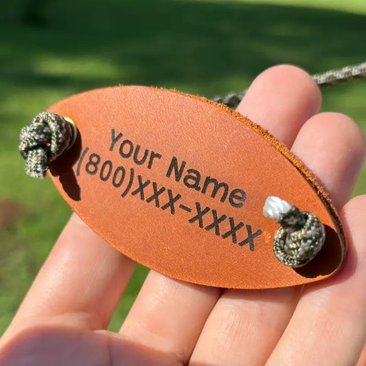 Personalized leather wrist cradle attached to a walking stick, engraved with a custom name and phone number example